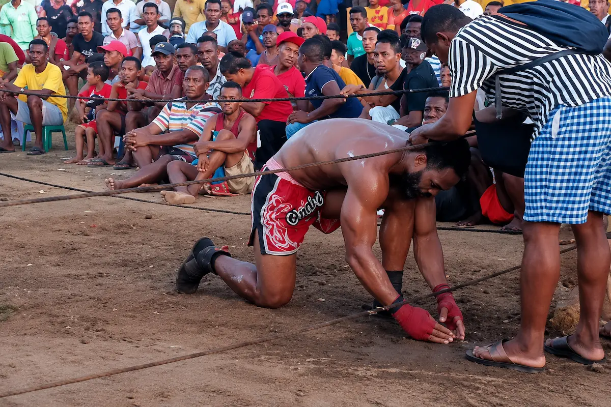 Kneeling Moraingy fighter preparing for traditional boxing match in Madagascar