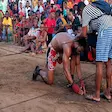 Kneeling Moraingy fighter preparing for traditional boxing match in Madagascar